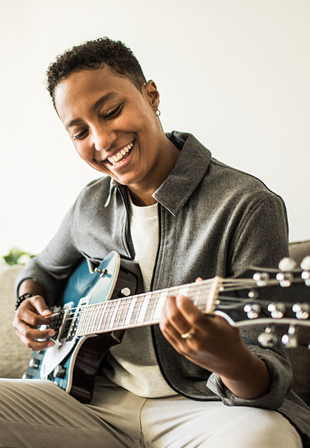 Woman smiling playing guitar
