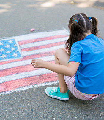 Girl with American flag drawn in sidewalk