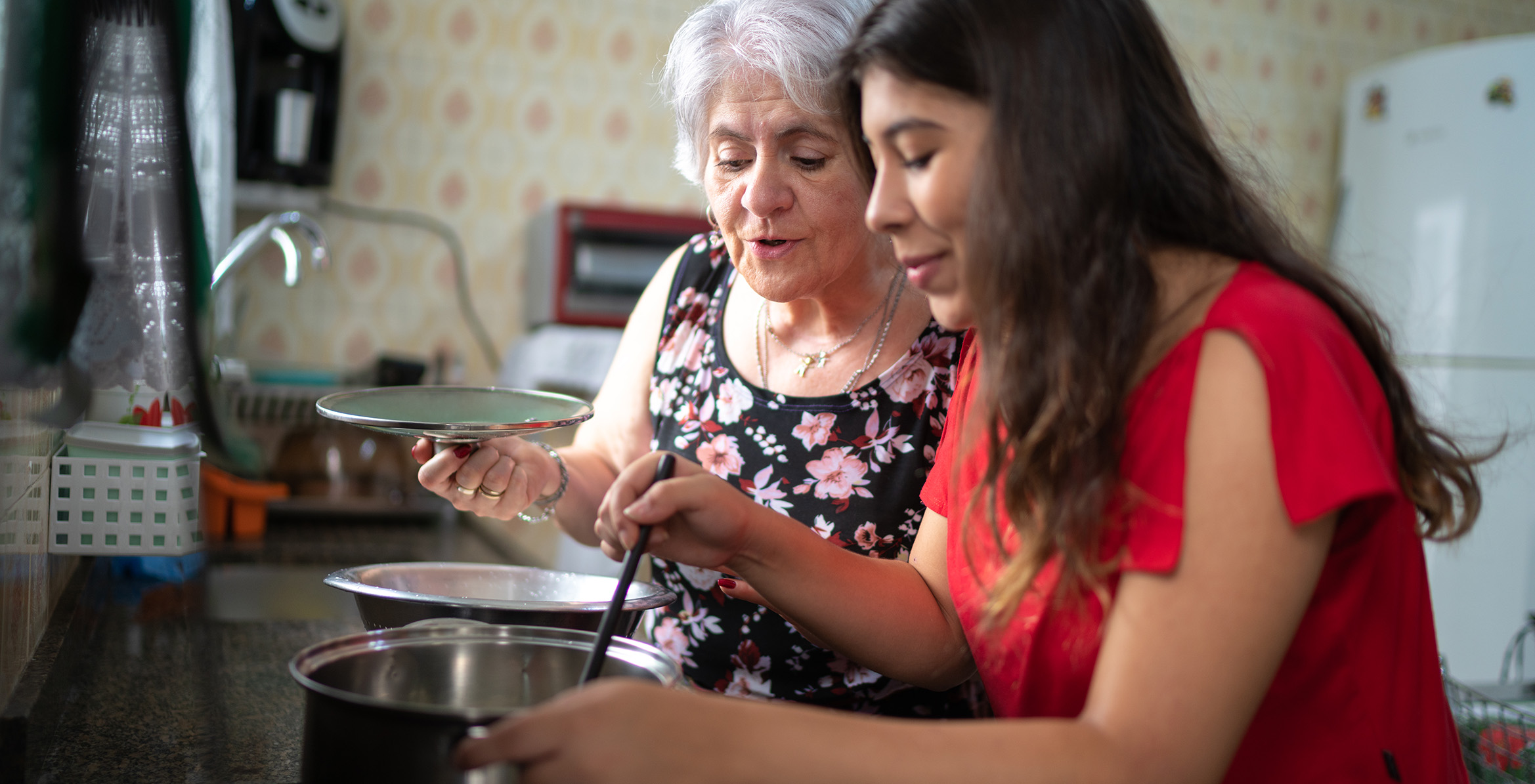 Grandmother teaching her granddaughter how to cook