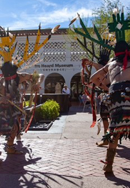Three Native Americans dancing in ceremonial dress