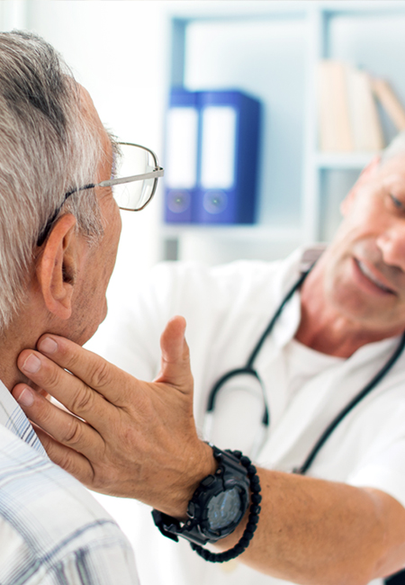 Male doctor doing thyroid check on senior man’s neck