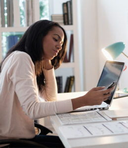 Tired looking woman working at desk on cell phone