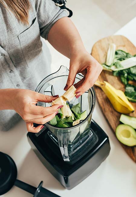 Woman preparing a healthy smoothie in blender