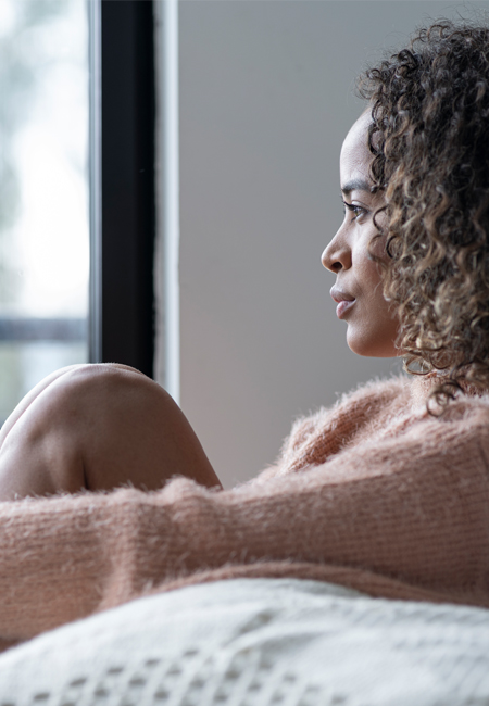 Woman sitting in living room looking off into distance