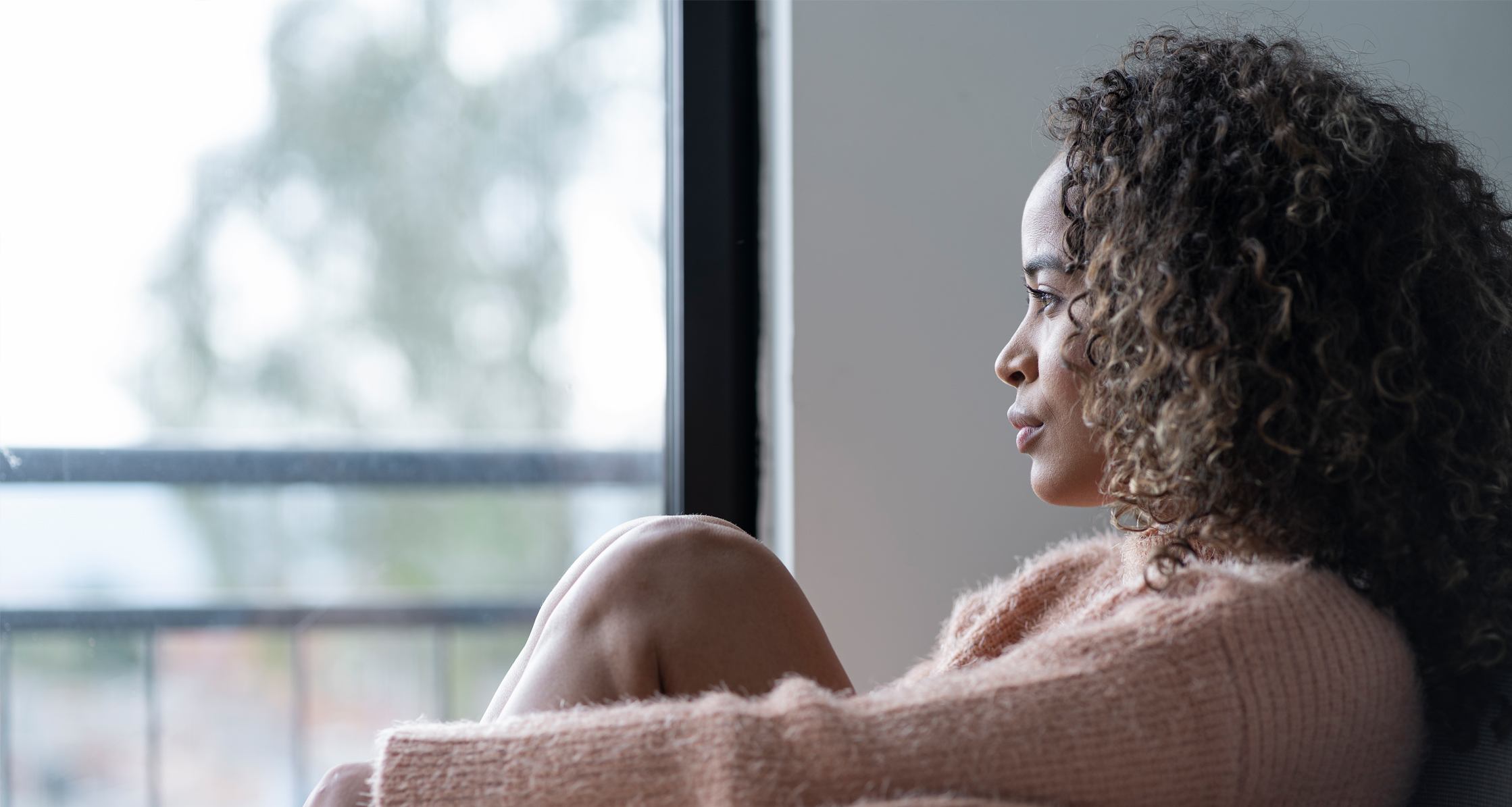 Woman sitting in living room looking off into distance