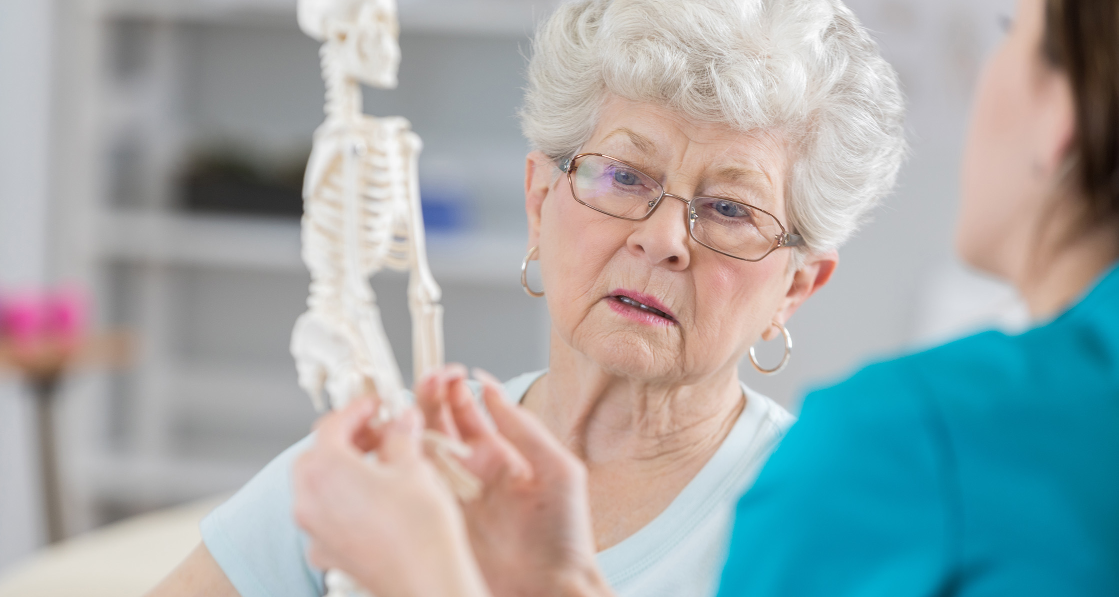 Senior woman discusses effects of osteoporosis with a physical therapist.
