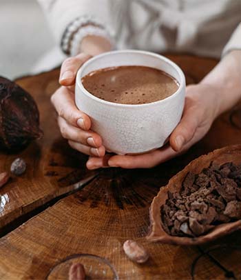 Woman’s hands holding healthy hot chocolate drink prepared from cocoa powder.