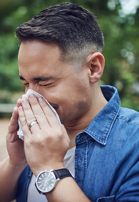 Man outdoors with allergy sneezing.