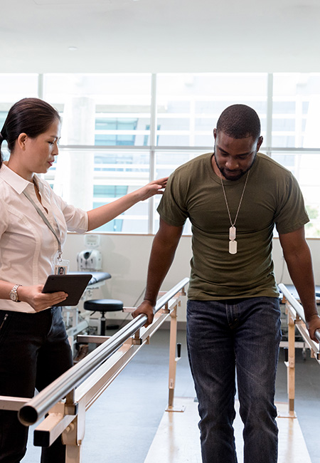 A physical therapist guides a military Veteran through physical therapy.