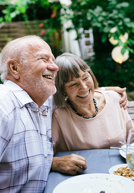 A senior couple enjoys an outdoor meal with family.