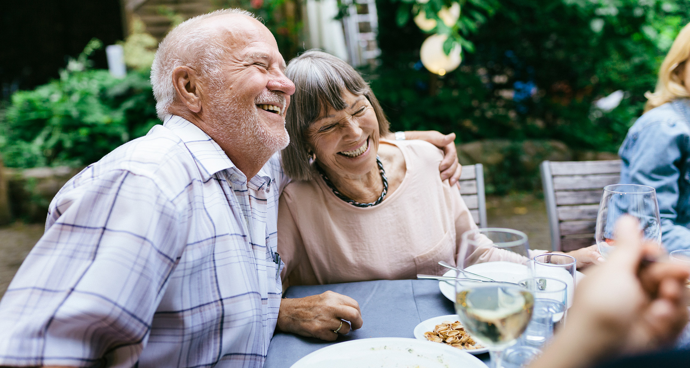 A senior couple enjoys an outdoor meal with family.