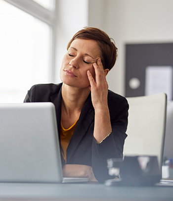 Businesswoman sitting in office, having a headache.