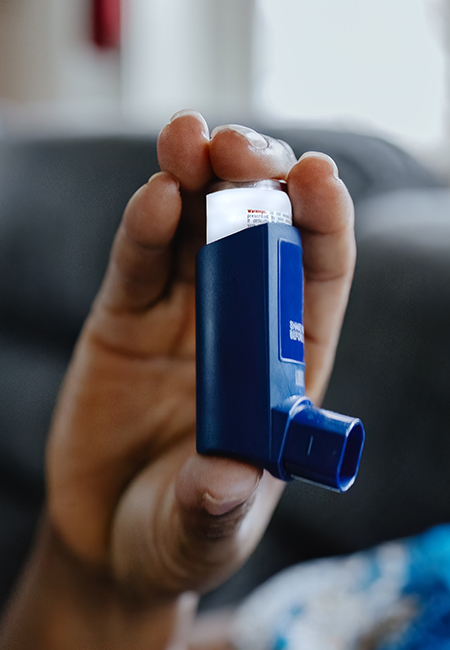 Woman holds an asthma inhaler.