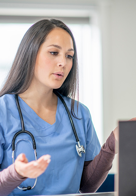 Medical worker sees patient virtually from her office.