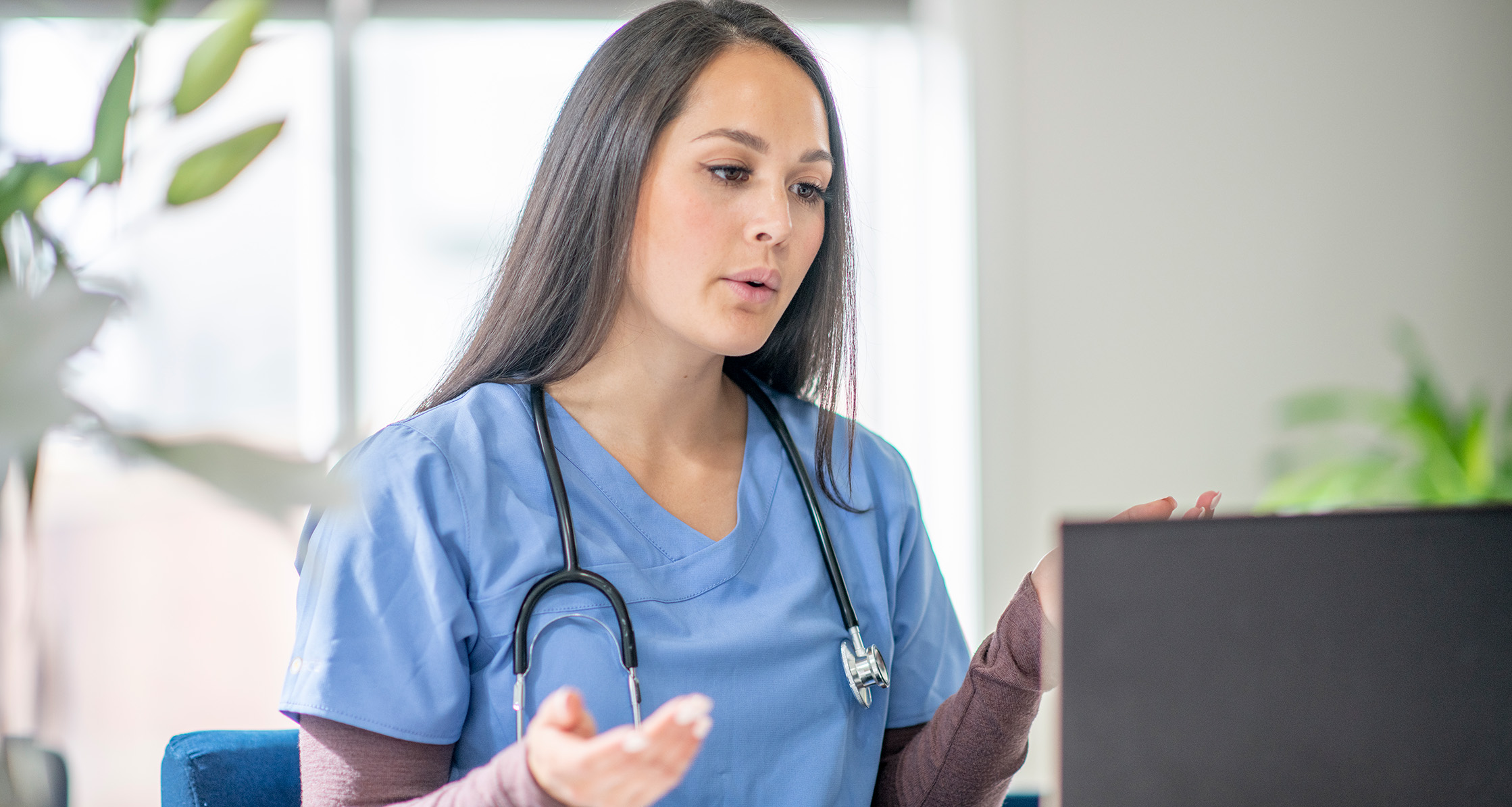 Medical worker sees patient virtually from her office.