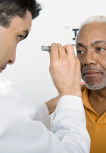 Doctor examines senior man’s eyesight.