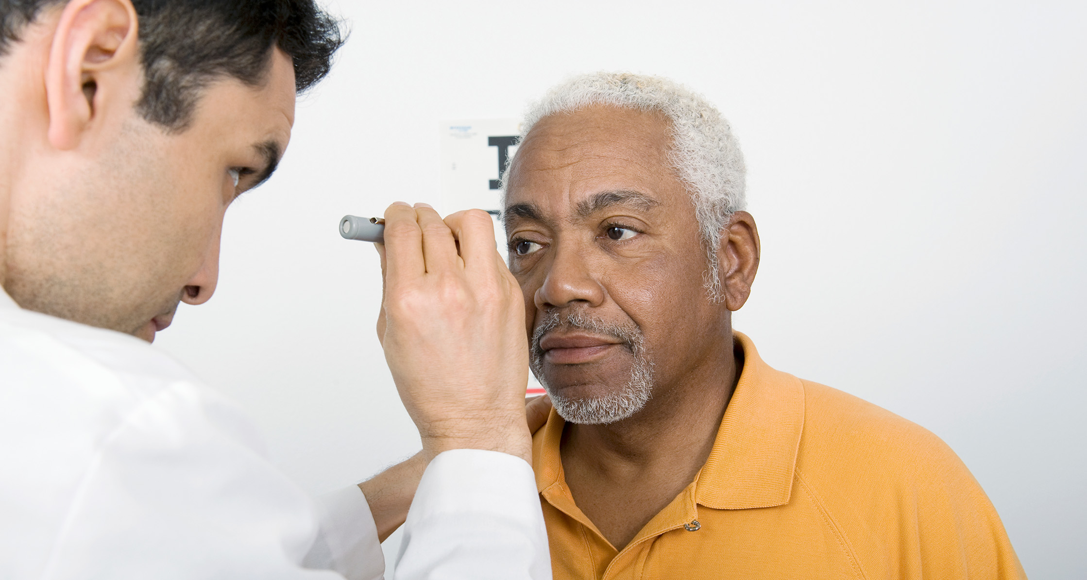 Doctor examines senior man’s eyesight.