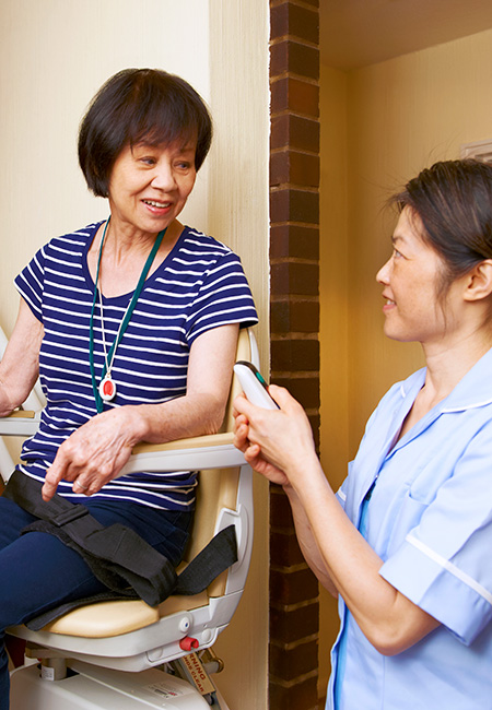 Senior woman on stair lift with nurse.