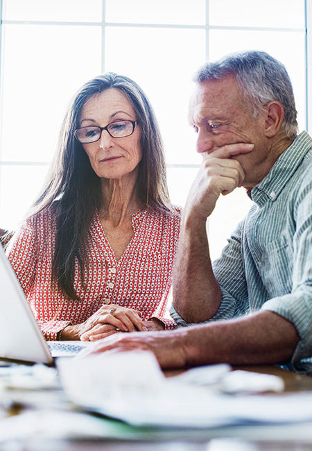 Senior couple using a computer to figure out bills.