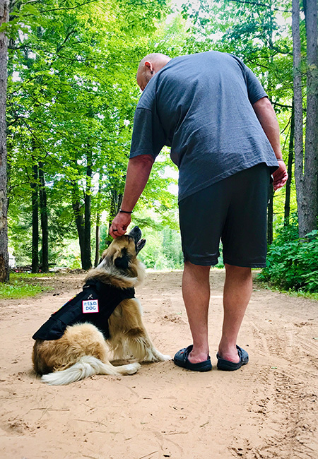 Mental health service dog and owner with PTSD working outdoors.
