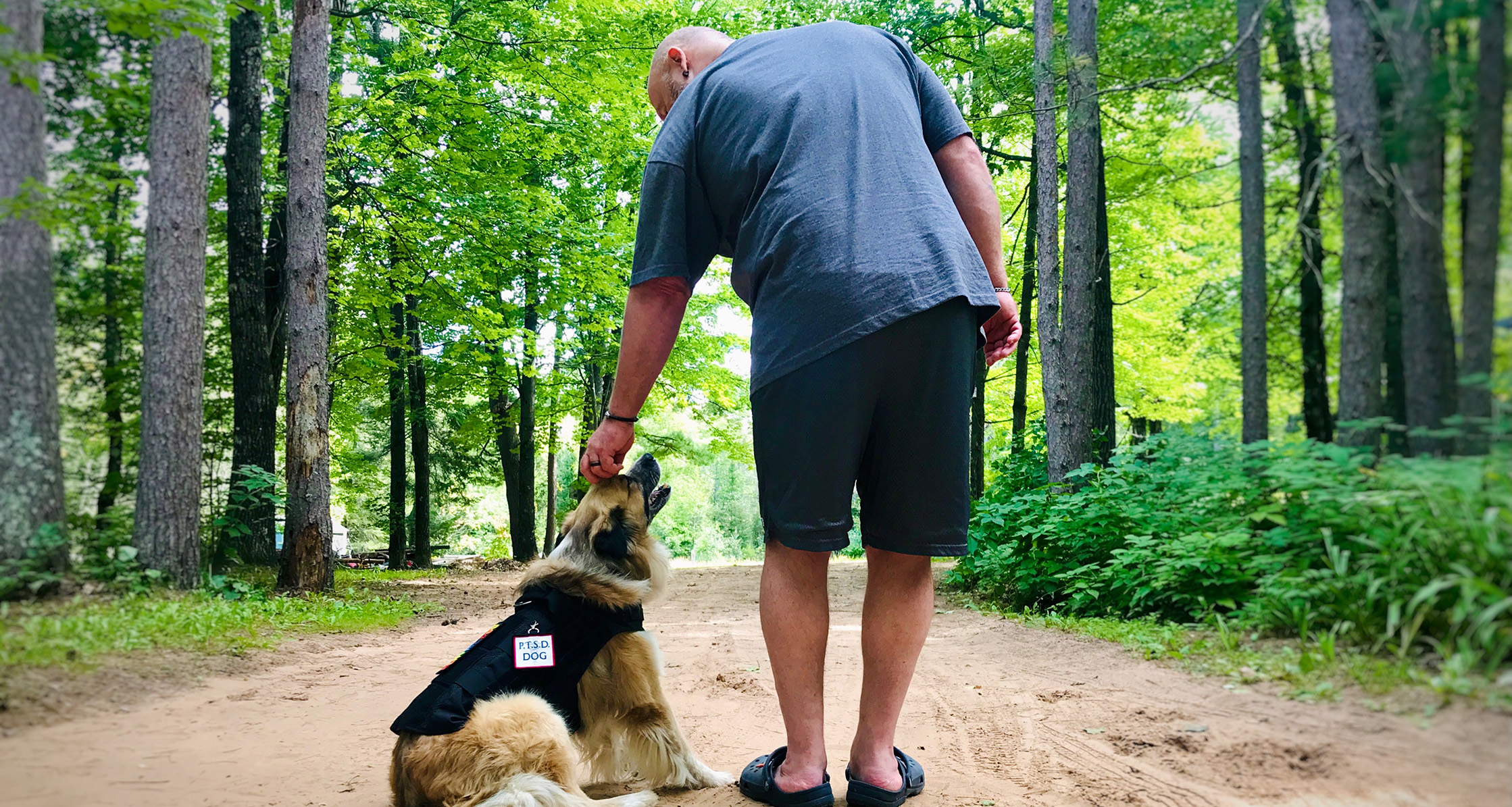 Mental health service dog and owner with PTSD working outdoors.