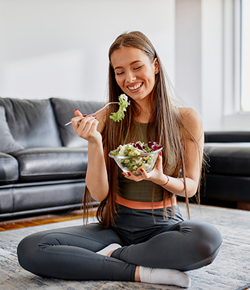 Young woman eating fresh vegetable salad.
