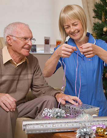 Woman helping a Veteran wrap a Christmas gift.