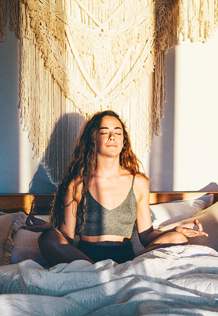 Woman meditating on bed after waking up.