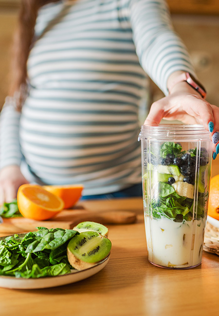 Pregnant woman making healthy smoothie.