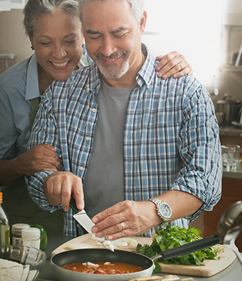 Hispanic couple cooking in kitchen.