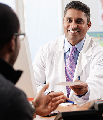 Doctor handing patient prescription in doctor's office.