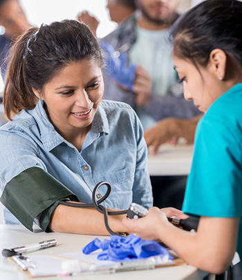 Female Veteran watches as a nurse takes blood pressure.