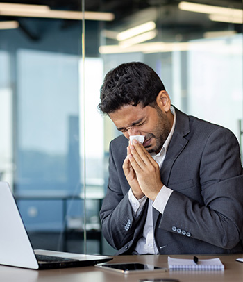 Man using tissue at work due to allergies.