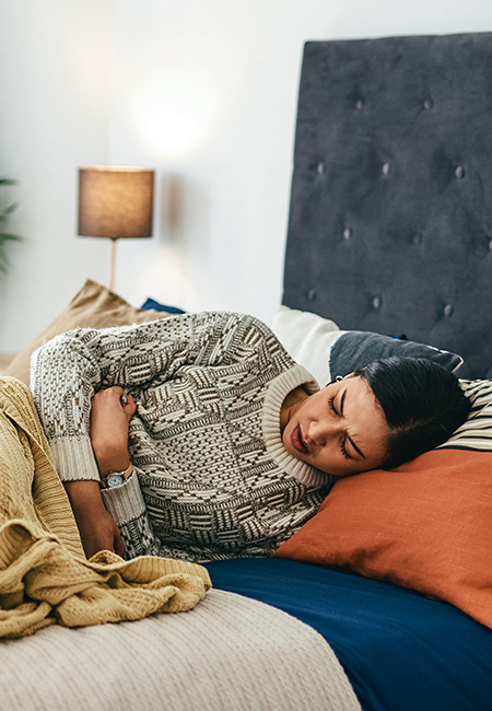 Women in bed with tummy pain.