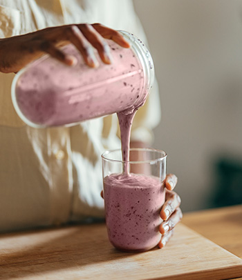 Woman pouring a smoothie into a glass.