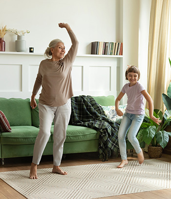 Grandmother dancing with granddaughter at home.