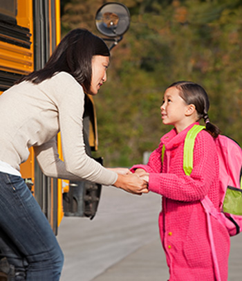 Mother talking to daughter as she gets on the school bus.