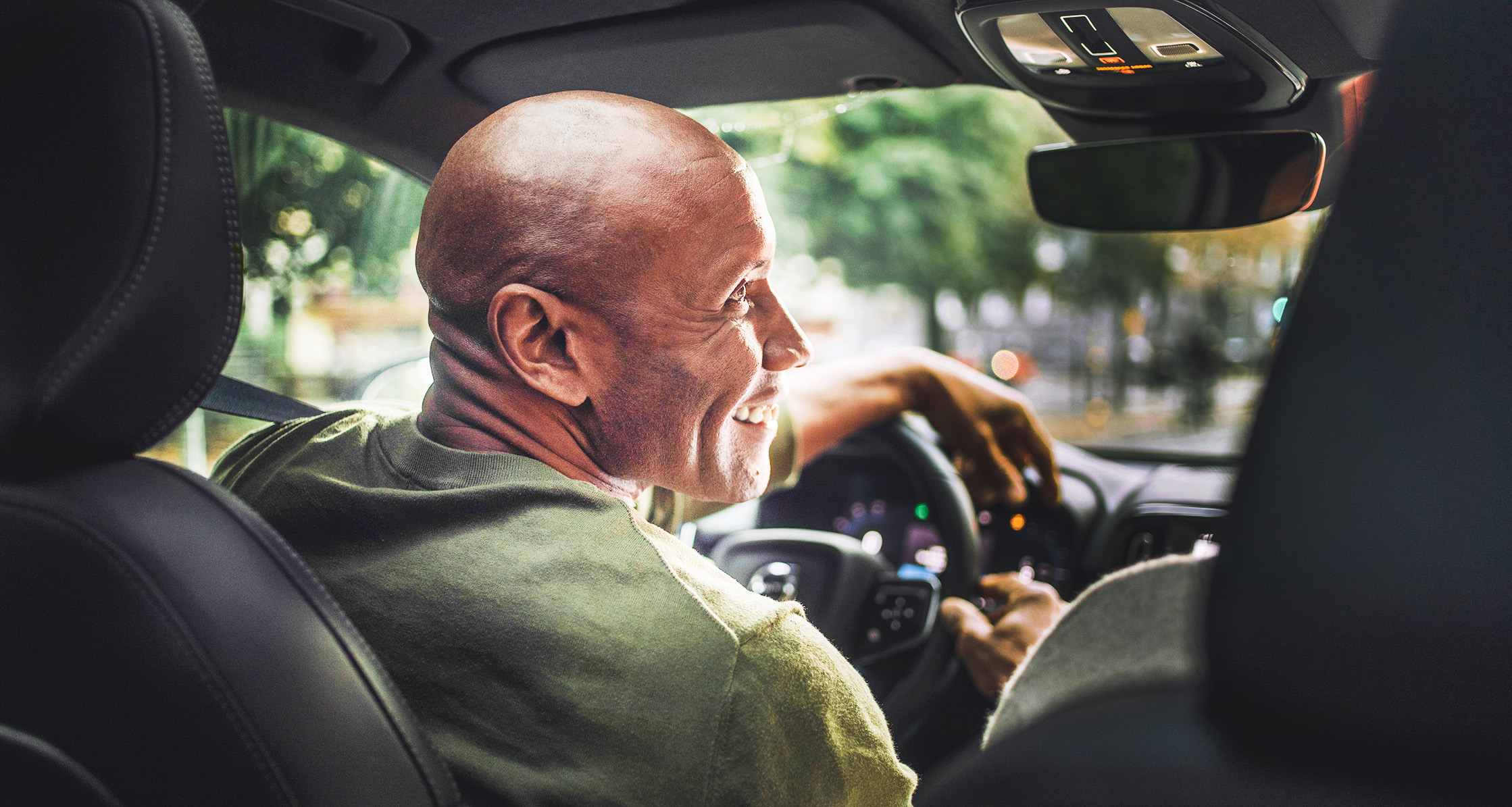 Smiling man looking away while driving in car.