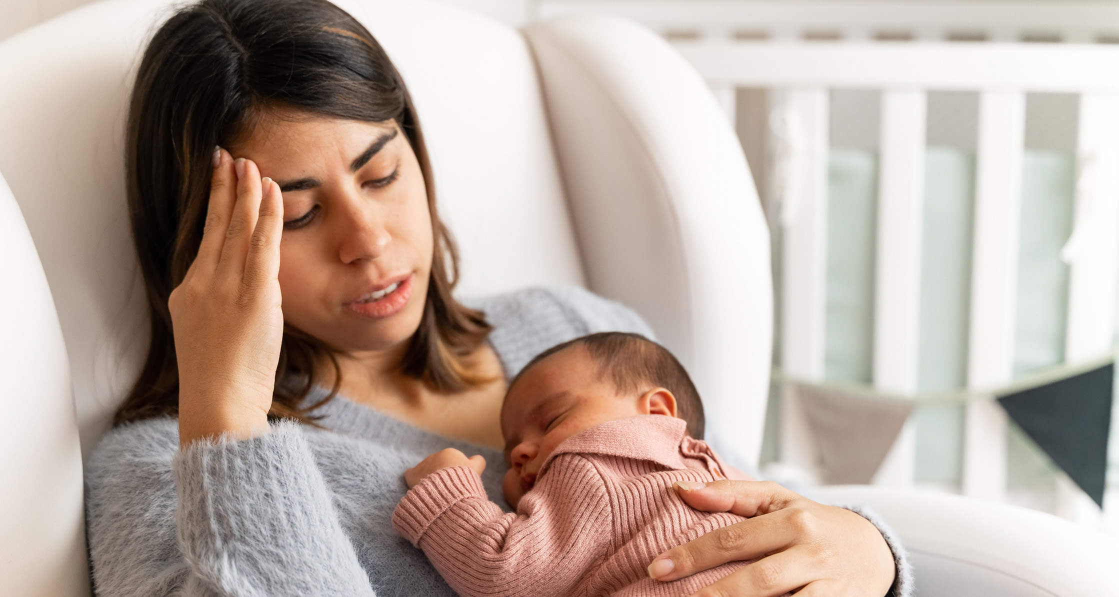 Mother sitting in nursery experiencing postpartum depression.