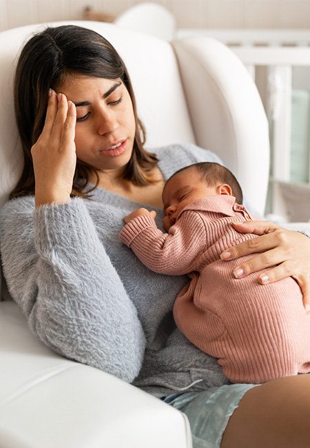 Mother sitting in nursery experiencing postpartum depression.