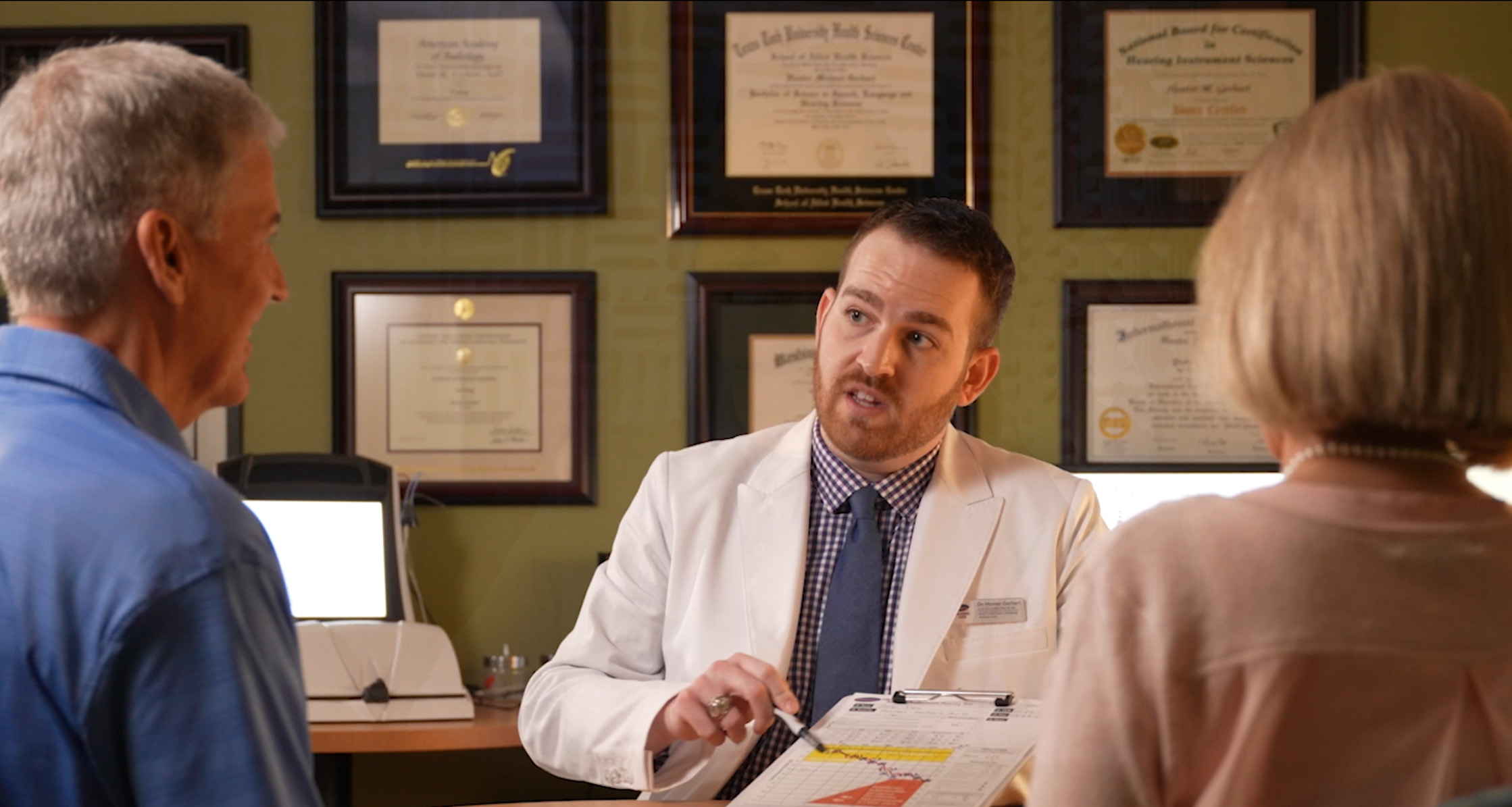 A retired couple is consulting with Dr. Hunter Gerhart, an audiologist.