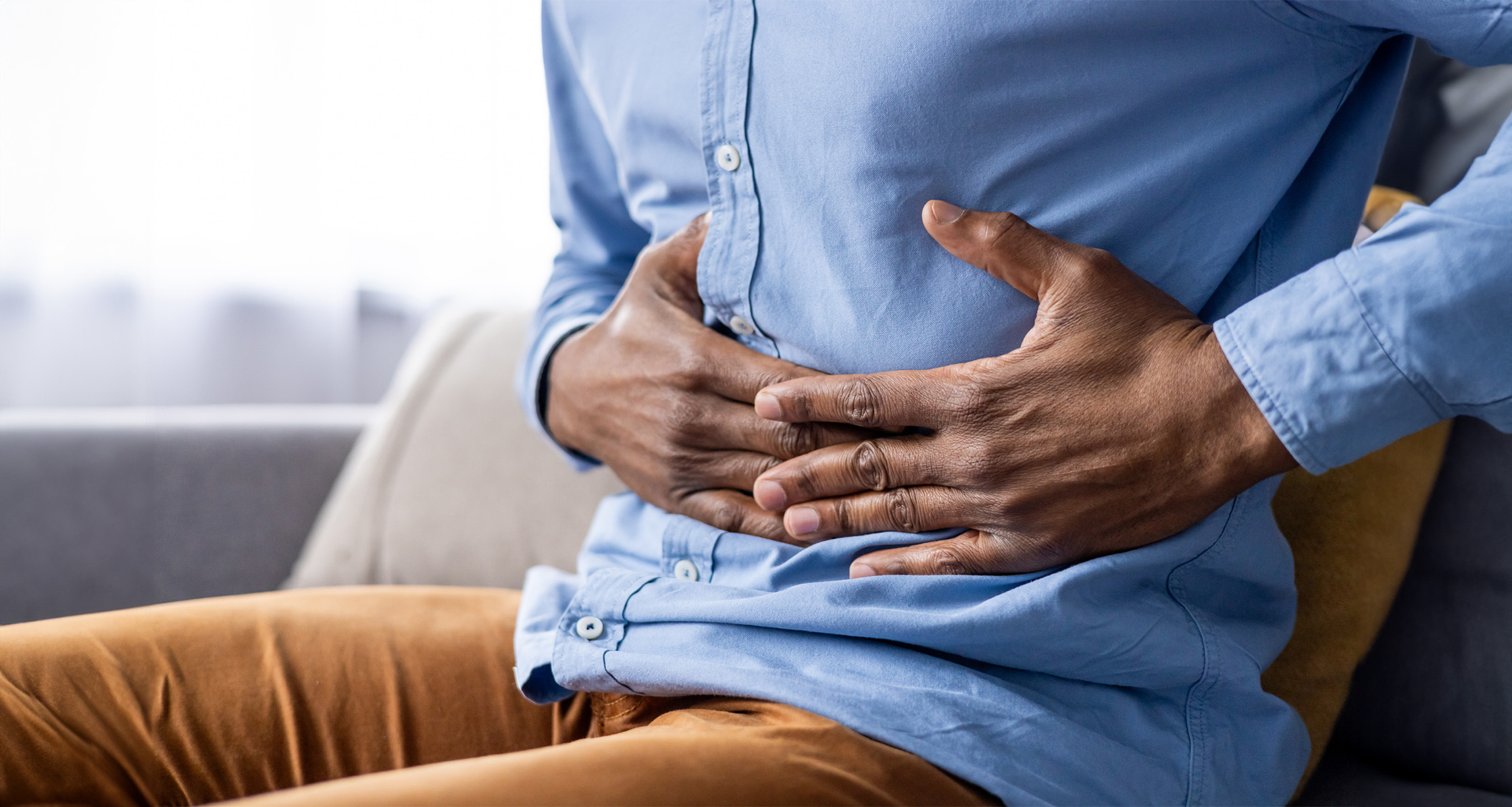 A man is shown clutching his stomach in pain, indicating gastrointestinal discomfort.