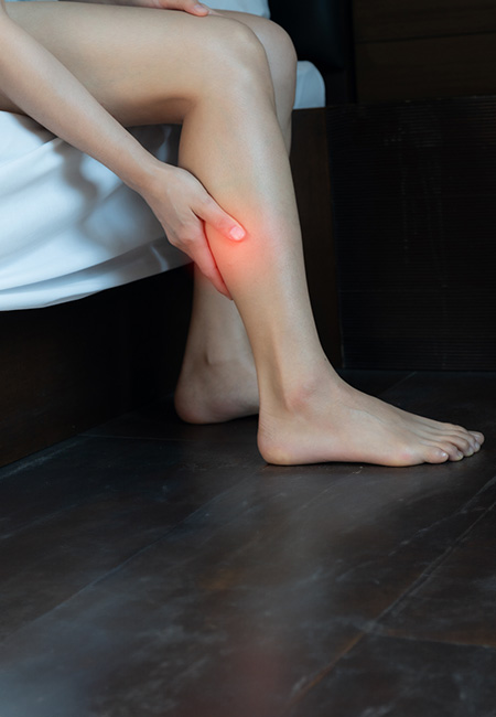 Woman massaging her calf due to calf pain, which may indicate a serious condition such as a blood clot.