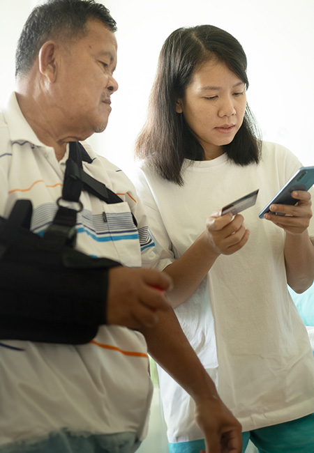 A young adult is helping her Veteran father use a smartphone to access his PACT Act benefits.