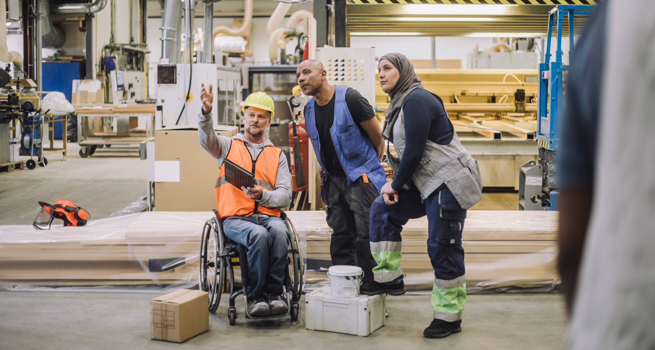 A Veteran in a wheelchair is explaining something to his colleagues.