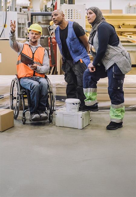 A Veteran in a wheelchair is explaining something to his colleagues.