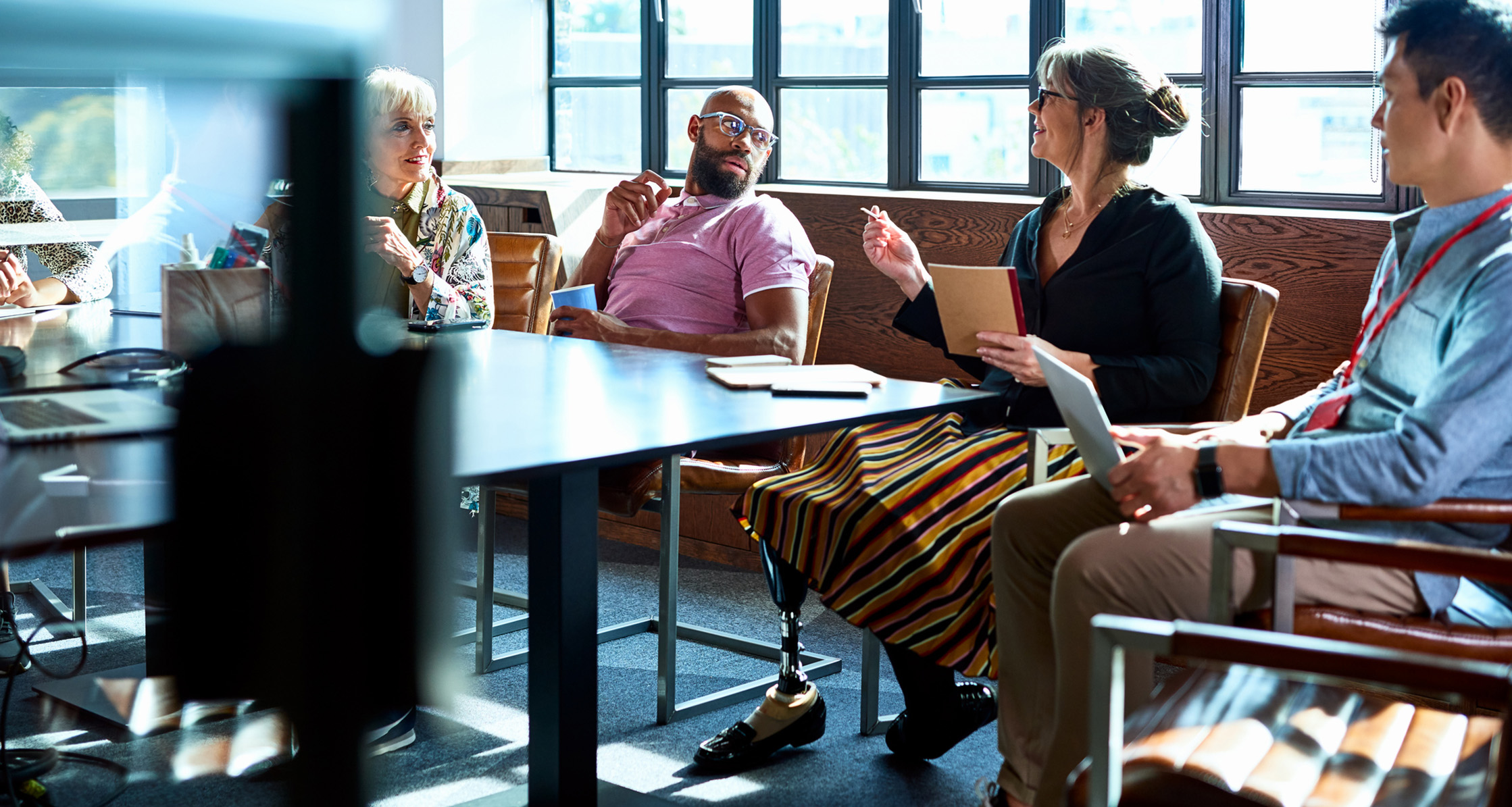 A Veteran with a prosthetic leg is leading a meeting with her coworkers.