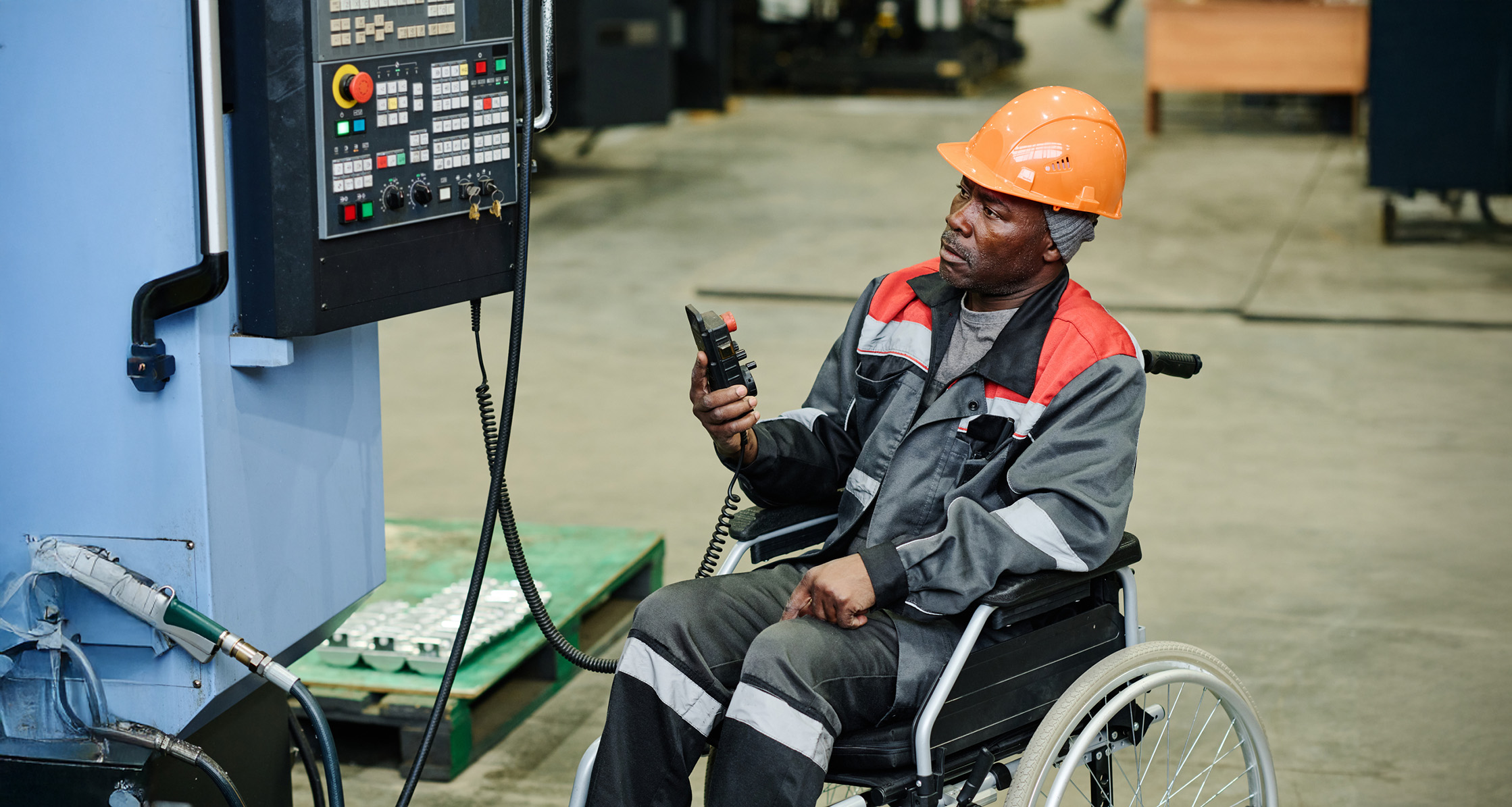 A Veteran worker in a wheelchair operating an industrial machine.