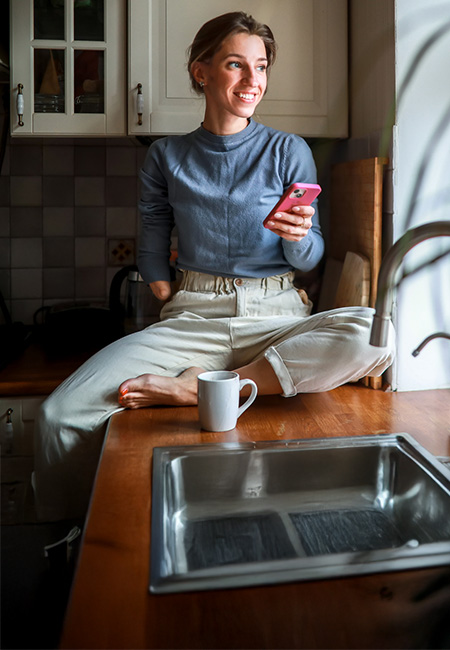 A disabled Veteran sits on a counter, legs crossed, reviewing her accomplishments on the phone.
