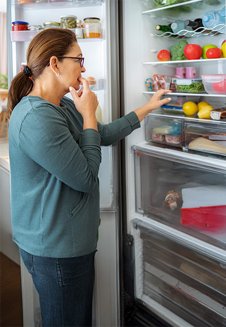 A woman is searching for a snack in the refrigerator.